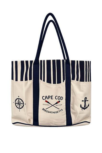 A canvas tote bag with navy blue and cream vertical stripes, featuring a navy blue handle. The front pockets are cream with navy blue graphics, including a compass rose on the left, an anchor on the right, and 'CAPE COD STRASSE MASSACHUSETTS' with crossed oars in the center.