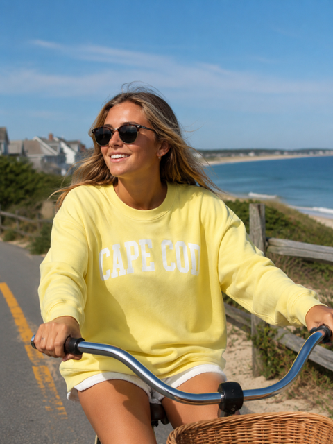 Girl riding a bicycle wearing a Cape Cod yellow crewneck