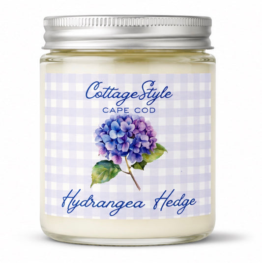 Candle jar with a label featuring hydrangea flowers and 'Cottage Style Cape Cod' text on a white background.